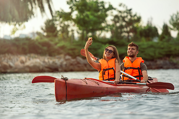 Image showing Happy couple kayaking on river with sunset on the background