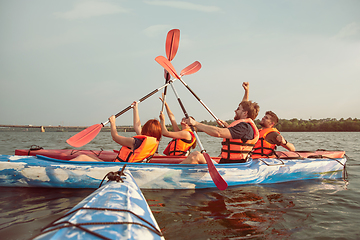 Image showing Happy friends kayaking on river with sunset on the background