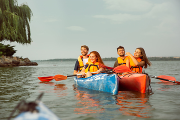 Image showing Happy friends kayaking on river with sunset on the background