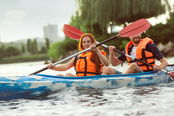 Image showing Happy couple kayaking on river with sunset on the background