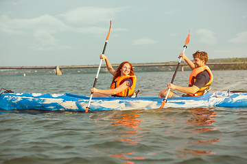 Image showing Happy couple kayaking on river with sunset on the background