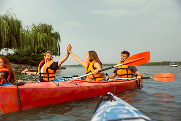 Image showing Happy friends kayaking on river with sunset on the background