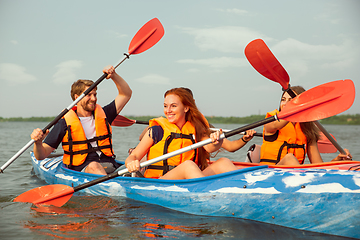 Image showing Happy friends kayaking on river with sunset on the background