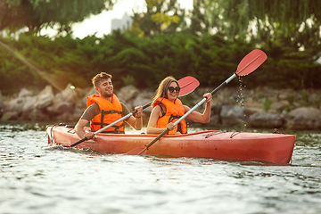 Image showing Happy couple kayaking on river with sunset on the background