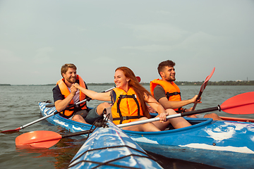 Image showing Happy friends kayaking on river with sunset on the background