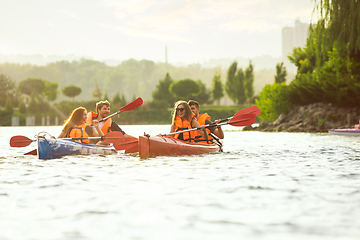 Image showing Happy friends kayaking on river with sunset on the background