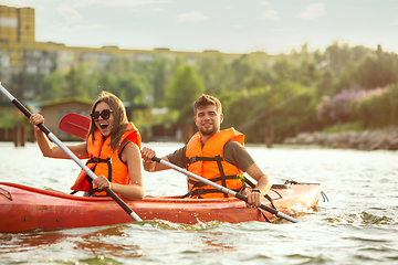 Image showing Happy couple kayaking on river with sunset on the background