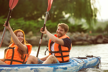 Image showing Happy couple kayaking on river with sunset on the background