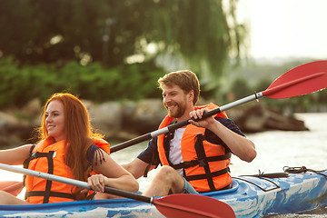 Image showing Happy couple kayaking on river with sunset on the background