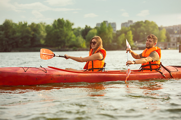 Image showing Happy couple kayaking on river with sunset on the background