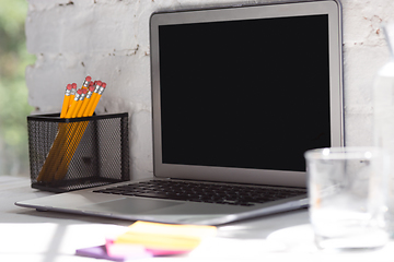 Image showing Mock up empty black laptop screen on white brick wall background