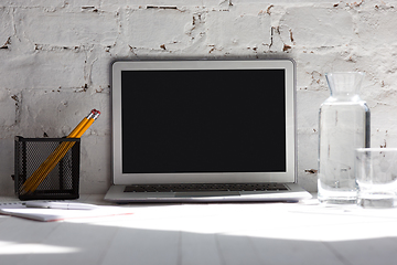 Image showing Mock up empty black laptop screen on white brick wall background