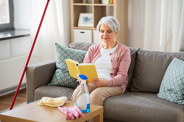 Image showing senior woman reading book after home cleaning