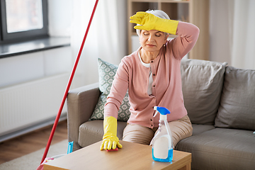 Image showing tired senior woman cleaning table at home