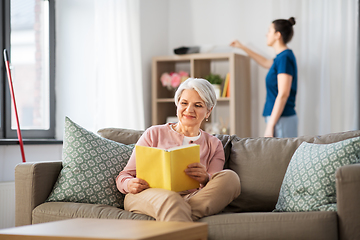 Image showing old woman reading book and housekeeper at home