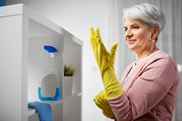 Image showing senior woman putting protective rubber gloves on