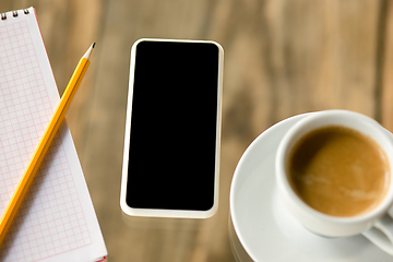 Image showing Mock up empty black smartphone screen on wooden table background