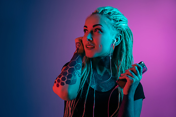 Image showing Caucasian young woman\'s portrait on gradient background in neon light