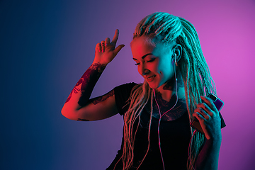 Image showing Caucasian young woman\'s portrait on gradient background in neon light