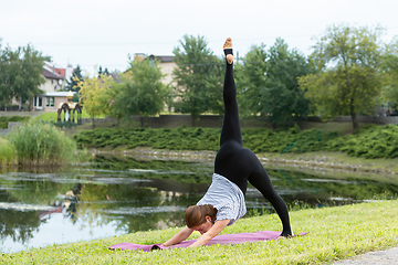 Image showing Young beautiful woman doing yoga exercise in green park. Healthy lifestyle and fitness concept.