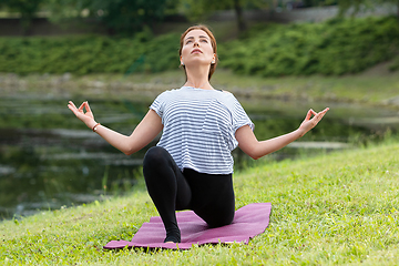 Image showing Young beautiful woman doing yoga exercise in green park. Healthy lifestyle and fitness concept.