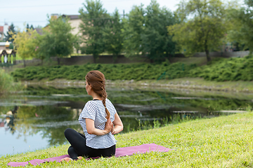 Image showing Young beautiful woman doing yoga exercise in green park. Healthy lifestyle and fitness concept.