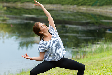 Image showing Young beautiful woman doing yoga exercise in green park. Healthy lifestyle and fitness concept.