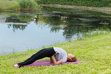 Image showing Young beautiful woman doing yoga exercise in green park. Healthy lifestyle and fitness concept.