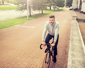 Image showing young man riding bicycle on city street