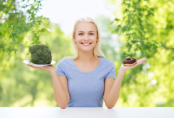 Image showing smiling woman choosing between broccoli and donut