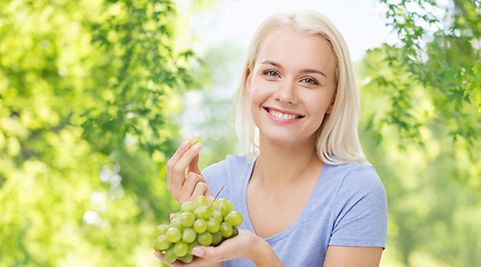 Image showing happy woman eating grapes