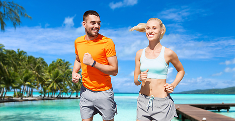 Image showing smiling couple running along exotic on beach