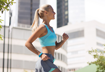 Image showing smiling young woman running at city