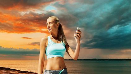 Image showing happy woman with smartphone exercising over sea