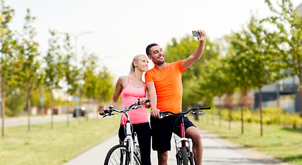 Image showing couple with bicycles taking selfie by smartphone