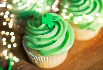 Image showing green cupcakes and shamrock on wooden table