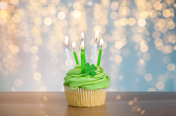 Image showing green cupcake with six burning candles on table