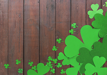 Image showing green paper shamrocks on wooden background