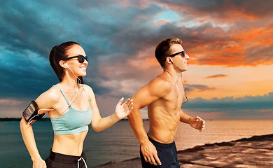 Image showing couple with phones and arm bands running over sea