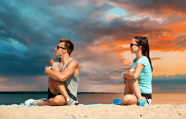 Image showing smiling couple stretching legs on beach