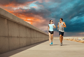 Image showing couple in sports clothes running along pier