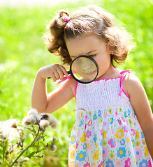 Image showing Young girl is looking at flower through magnifier