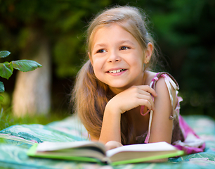 Image showing Little girl is reading a book outdoors