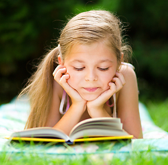 Image showing Little girl is reading a book outdoors