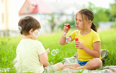 Image showing Little girl and boy are blowing soap bubbles