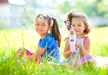 Image showing Two little girls are blowing soap bubbles