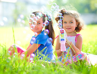 Image showing Two little girls are blowing soap bubbles