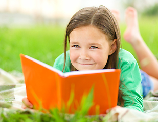 Image showing Little girl is reading a book outdoors