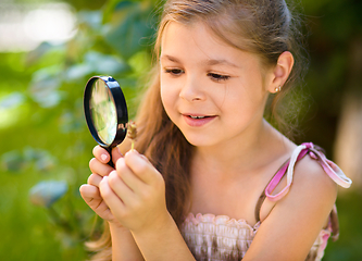 Image showing Young girl is looking at flower through magnifier