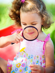 Image showing Young girl is looking at flower through magnifier